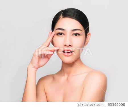 young beautiful asian woman with clean and bright skin, Cosmetic Beauty Concept,hands touch on the cheek, smiling and friendly face isolated on grey background 63399008