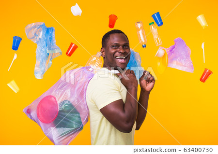 Problem of trash, plastic recycling, pollution and environmental concept - funny man carrying garbage bag on yellow background 63400730