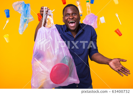 Problem of trash, plastic recycling, pollution and environmental concept - funny man carrying garbage bag on yellow background 63400732