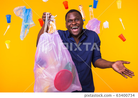 Problem of trash, plastic recycling, pollution and environmental concept - funny man carrying garbage bag on yellow background 63400734