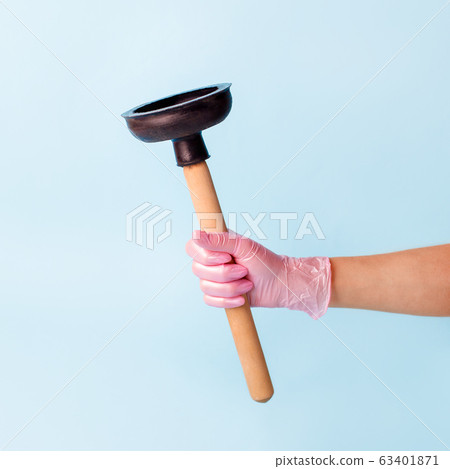 Hand in pink glove holding domestic plunger. Hand in pink glove holding domestic plunger. 63401871