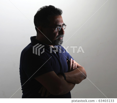 A smiling Indian man with a goatee in a studio against a white background. Wearing spectacles and looking away from camera to the right A smiling Indian man with a goatee in a studio against a white background. Wearing spectacles and looking away from camera to the right 63403133