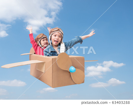 Asian siblings cute girl playing cardboard airplane on blue sky background with clipping path. Two asian children play as pilot on cardboard airplane DIY. Asian siblings cute girl playing cardboard airplane on blue sky background with clipping path. Two asian children play as pilot on cardboard airplane DIY. 63403288