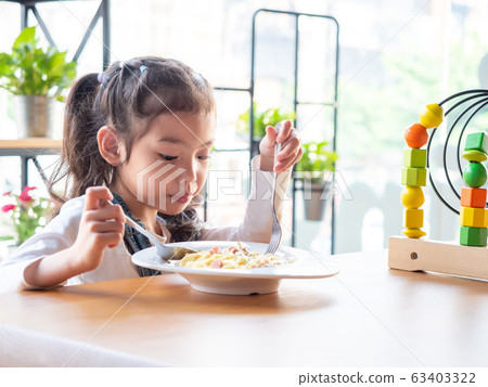 Portrait of asian little cute girl 6 years old eating spaghetti by herself on wooden table. Portrait of asian little cute girl 6 years old eating spaghetti by herself on wooden table. 63403322