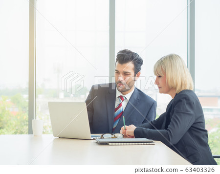 Business man and woman talking together and looking laptop on table at meeting room. Teamwork, partnership concept 63403326