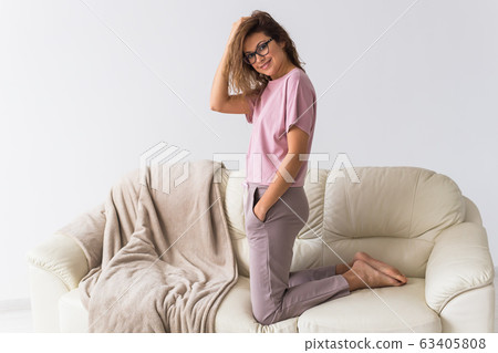 Young attractive woman dressed in beautiful colorful pajama posing as a model in her living room. Comfortable sleepwear, home relaxation and female fashion concept. Young attractive woman dressed in beautiful colorful pajama posing as a model in her living room. Comfortable sleepwear, home relaxation and female fashion concept. 63405808
