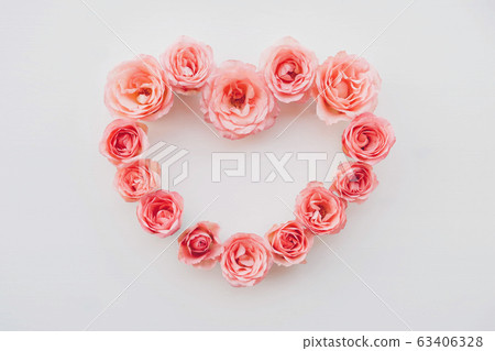 Heart frame of fresh pink roses in full bloom on white background. Heart frame of fresh pink roses in full bloom on white background. 63406328