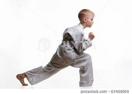 Martial arts student crouches and stretches his 63408069