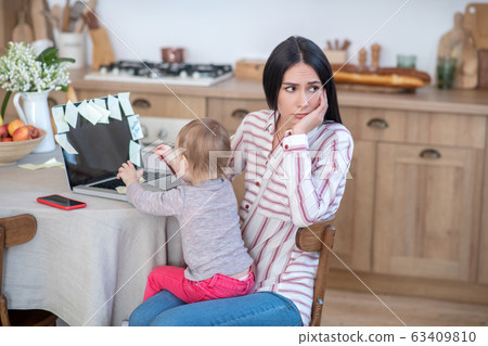 Stressed mom holding daughter, kid disturbing her 63409810