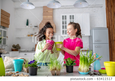 Two cute teens looking amused while planting flowers 63411517