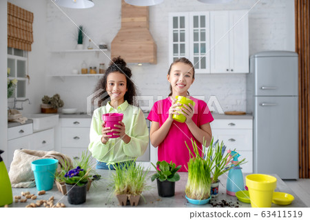 Two cute teens standing with flower pots in their hands 63411519