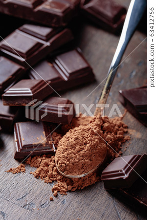 Broken chocolate pieces and cocoa powder . Broken chocolate pieces and cocoa powder . 63412756