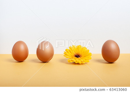 Spring and easter concept. A row of brown eggs and a yellow flower 63413060