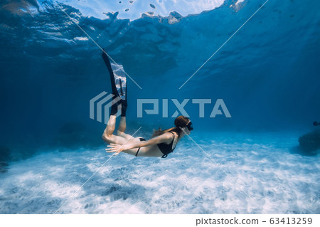 Woman free diver glides with white sand over sandy sea. Freediving underwater in Hawaii island 63413259
