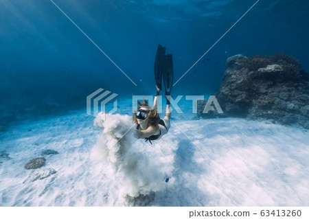 Woman free diver glides with white sand over sandy sea. Freediving underwater in Hawaii island 63413260