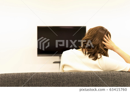A rear view of a young woman watching TV 63415760