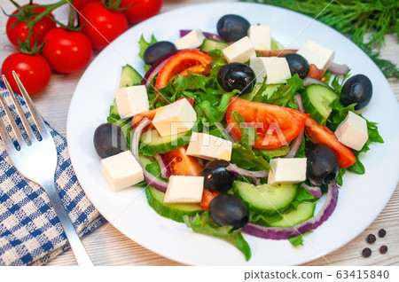 Greek salad with tomatoes, cucumbers and feta cheese with olives on the table 63415840
