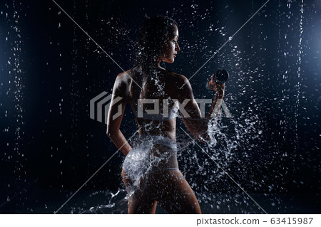 athletic woman pumping up muscles with dumbbells athletic woman pumping up muscles with dumbbells 63415987