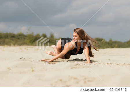 Gorgeous young female crawling on beach 63416542