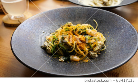 Sado oyster pasta with karasumi on a black plate 63417133