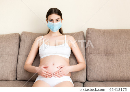 Pregnant woman in protective medical mask 63418175