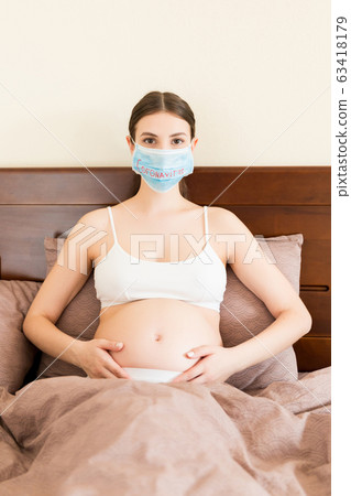 Pregnant woman in protective medical mask Pregnant woman in protective medical mask 63418179
