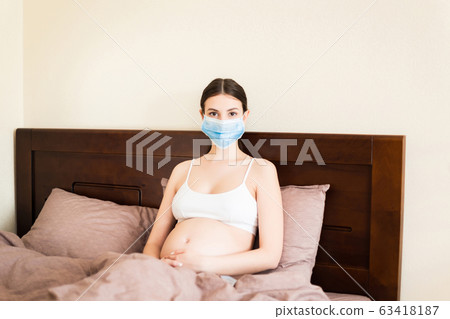 Pregnant woman in protective medical mask 63418187