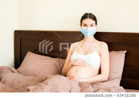 Pregnant woman in protective medical mask 63418188