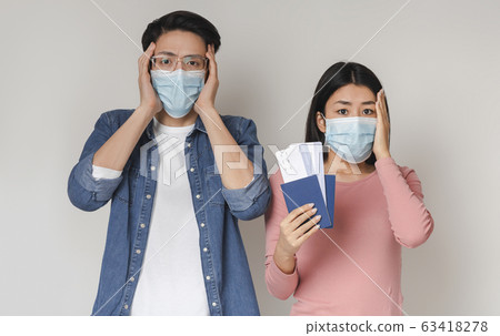 Panicked Chinese Couple Wearing Medical Masks Holding Passports And Tickets 63418278