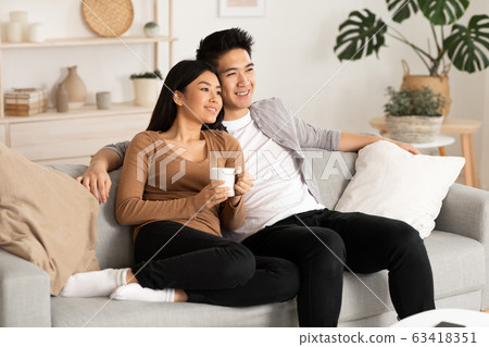 Filipino couple resting at home and watching tv Filipino couple resting at home and watching tv 63418351