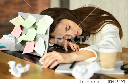 Young woman sleeping in front of laptop Young woman sleeping in front of laptop 63418495