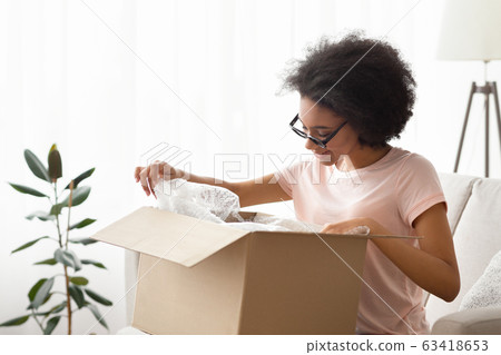 Girl in glasses unpacks purchase and considers it Girl in glasses unpacks purchase and considers it 63418653