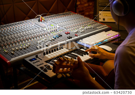 music composer playing guitar and midi keyboard for recording in home studio 63420730