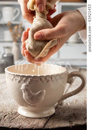 Straining poppy seed milk through a milk bag 63421453