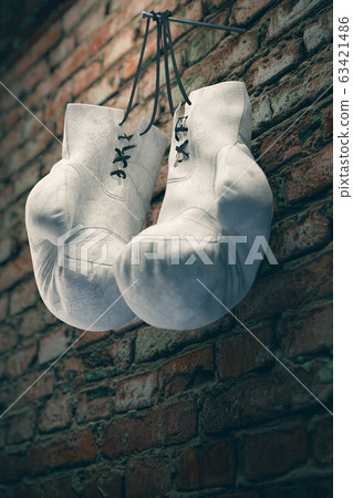 Old white boxing gloves hang on nail on brick wall with copy space for text. High resolution 3D rendering 63421486