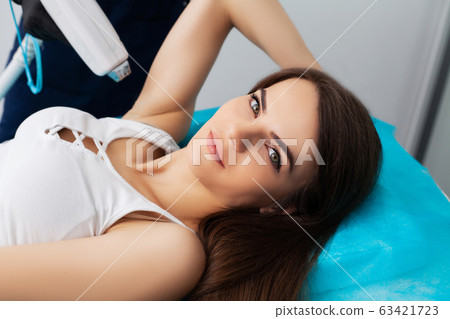 Pretty young woman receives laser hair removal for legs at beauty salon 63421723