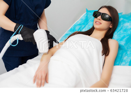 Pretty young woman receives laser hair removal for legs at beauty salon Pretty young woman receives laser hair removal for legs at beauty salon 63421728