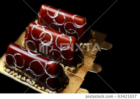 Three chocolate desserts with chocolate mirror glaze peanuts and silver circles decoration Three chocolate desserts with chocolate mirror glaze peanuts and silver circles decoration 63421837
