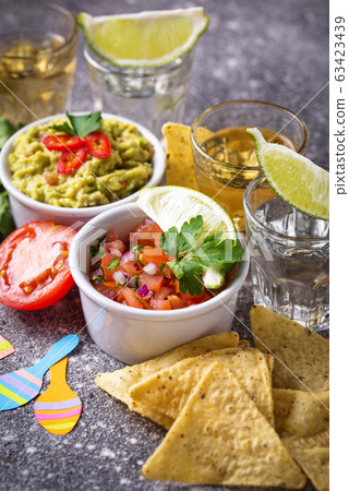 Guacamole, salsa, nachos and tequila 63423439