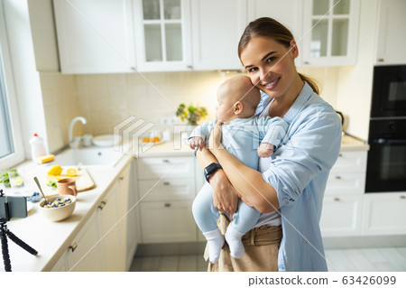 Happy young mother playing with her baby in the kitchen 63426099