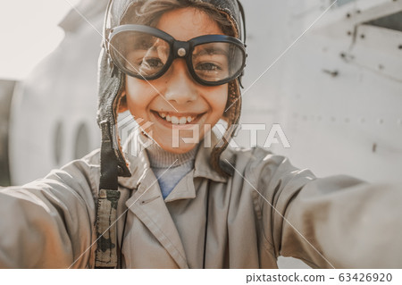 Smiling cute kid in aviator hat making photo outdoors Smiling cute kid in aviator hat making photo outdoors 63426920