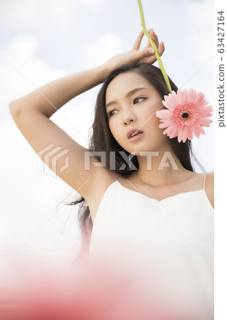 Portrait of a woman holding a flower in her hand Portrait of a woman holding a flower in her hand 63427164