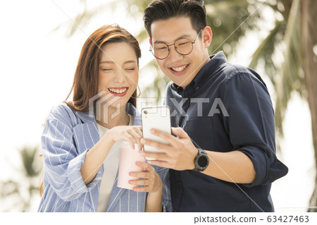 Men and women watching smartphone outdoors 63427463