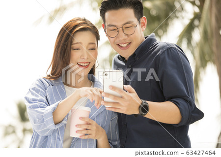 Men and women watching smartphone outdoors 63427464