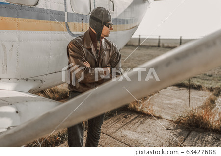 Confident man in aviator hat staying near plane 63427688