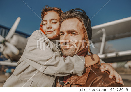 Smiling young man hugging his son outdoors 63428049