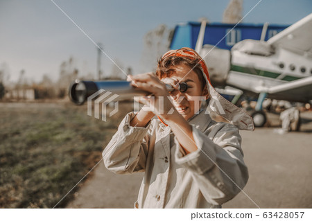 Happy kid looking through telescope near an airplane 63428057