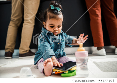Cute Afro American baby with cellphone sitting on the floor 63428591