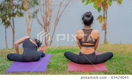 Rear view of attractive Asian girls in sportswear, sitting in lotus positions while doing yoga. 63429045