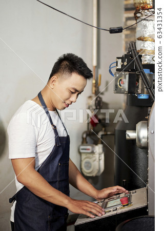 Man operating coffee roasting machine 63431354